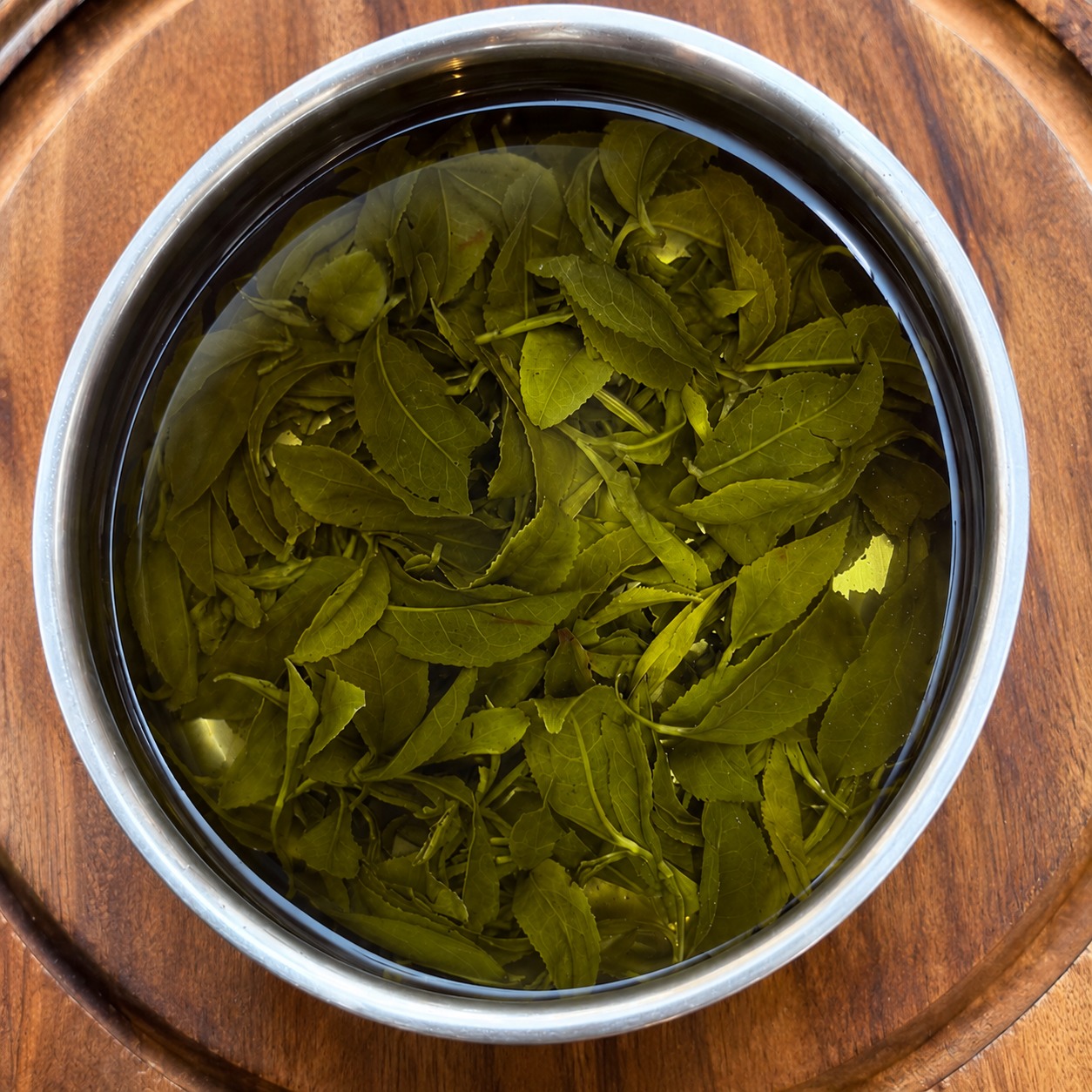 Fresh MOFS tea leaves resting in a wooden bowl